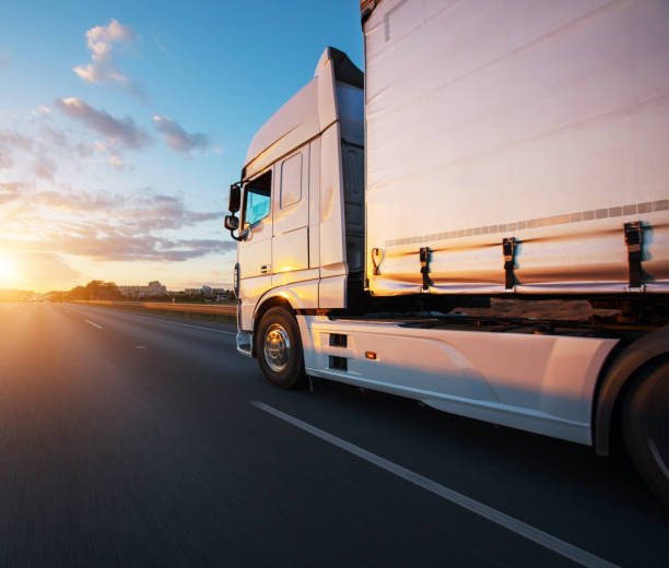 Loaded European truck on motorway in beautiful sunset light. On the road transportation and cargo.